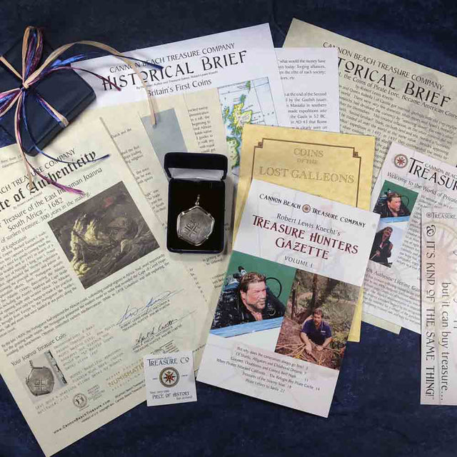 A shipwreck treasure coin pendant displayed in a black box amidst a package of documents. Text includes: "Cannon Beach Treasure Company," "Certificate of Authenticity," "Historical Brief," "Treasure Hunters Gazette," and "Coin Classification." Context is a deep blue textured surface.