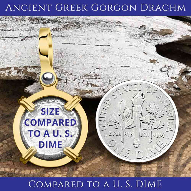 A gold-framed ancient Greek Gorgon silver Drachm coin pendant lies beside a U.S. dime on a textured surface. Text overlay on the coin pendant reads: "SIZE COMPARED TO A U.S. DIME."
